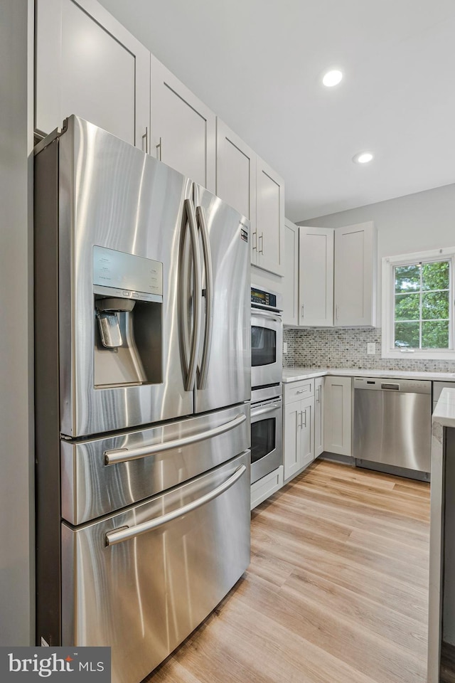 9310 Saffron Hill Ct, Manassas, VA 20110 - kitchen featuring appliances with stainless steel finishes, light countertops, tasteful backsplash, light wood finished floors, and recessed lighting