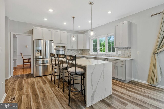 9310 Saffron Hill Ct, Manassas, VA 20110 - kitchen featuring stainless steel appliances, a sink, light stone countertops, light wood finished floors, and recessed lighting