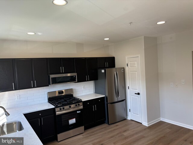 1853TOBIASDRIVESE Tobias Dr SE, Washington, DC 20020 - kitchen with stainless steel appliances, dark cabinetry, a sink, light wood-type flooring, and recessed lighting