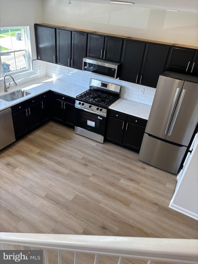 1853TOBIASDRIVESE Tobias Dr SE, Washington, DC 20020 - kitchen featuring appliances with stainless steel finishes, a sink, dark cabinetry, light wood-style flooring, and backsplash