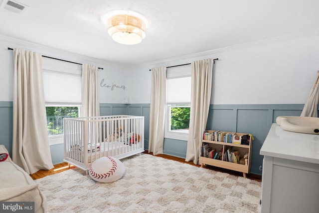 328 Avondale Ave, Haddonfield, NJ 08033 - bedroom with multiple windows, a decorative wall, a nursery area, ornamental molding, and wood finished floors