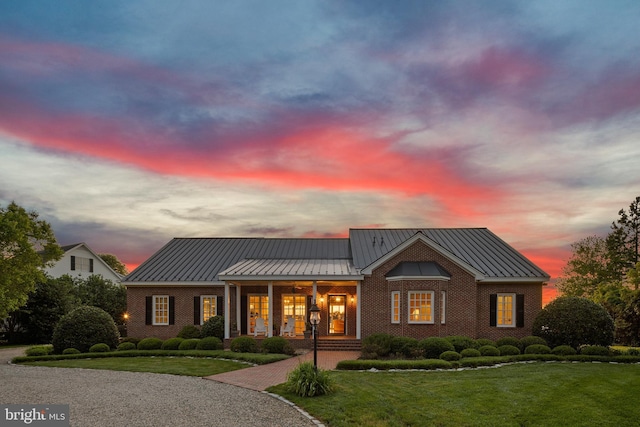 125 Oyster Pt, White Stone, VA 22578 - view of front of house featuring a standing seam roof, brick siding, covered porch, and a lawn
