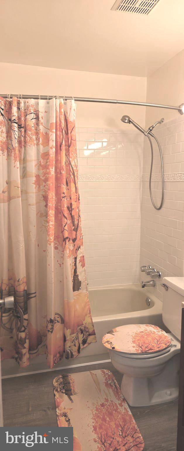 6924 Woodstream Ln, Lanham, MD 20706 - bathroom with shower / bath combo with shower curtain, toilet, and wood finished floors