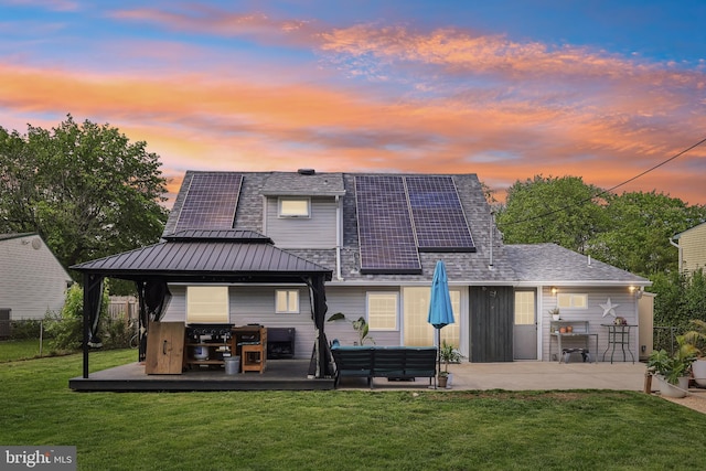 39 Village Ln, Levittown, PA 19054 - back of house at dusk with a gazebo, solar panels, an outdoor living space, a patio, and a standing seam roof