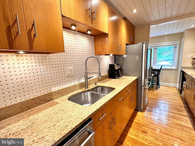 kitchen featuring a sink, light wood-style floors, brown cabinetry, backsplash, and wood ceiling