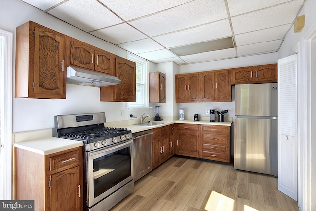 2530 18th St N, Arlington, VA 22201 - kitchen featuring stainless steel appliances, under cabinet range hood, a drop ceiling, light wood-style flooring, and light countertops