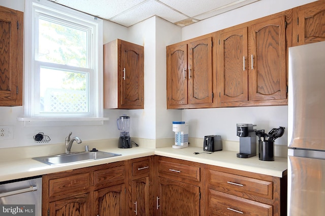 2530 18th St N, Arlington, VA 22201 - kitchen with appliances with stainless steel finishes, a sink, healthy amount of natural light, brown cabinetry, and a paneled ceiling