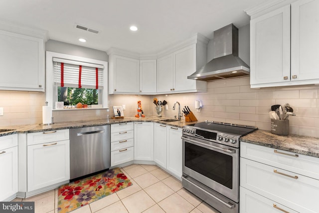105 Bayview Ln, Hague, VA 22469 - kitchen featuring stainless steel appliances, wall chimney exhaust hood, light tile patterned flooring, white cabinets, and a sink