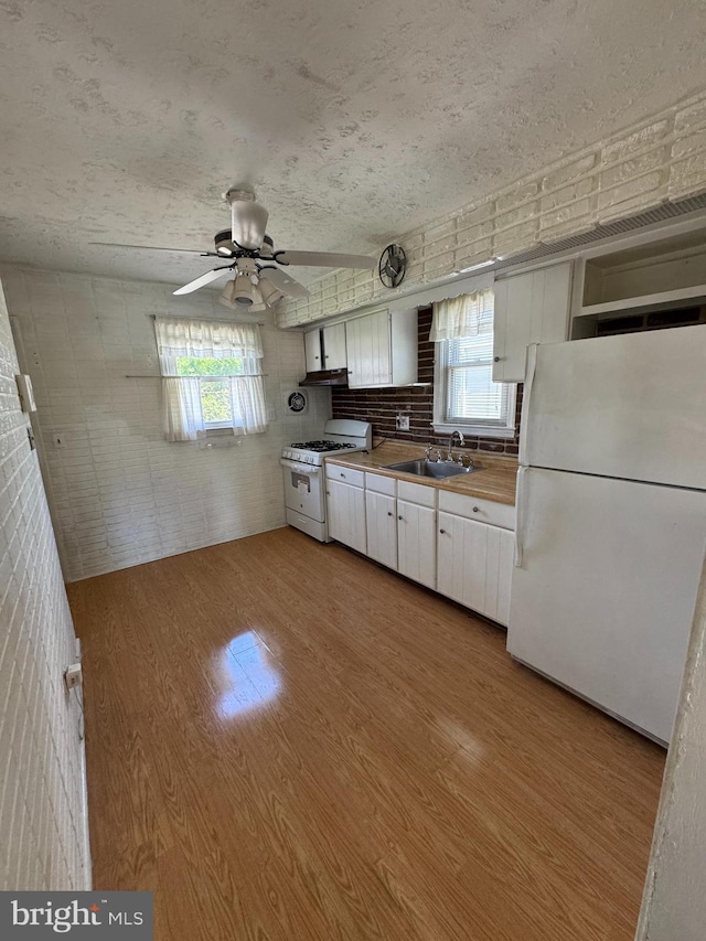 kitchen featuring white appliances, a sink, light wood-type flooring, white cabinets, and ceiling fan
