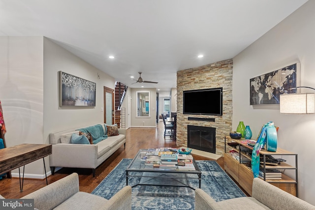 living room featuring ceiling fan, wood finished floors, baseboards, recessed lighting, and a stone fireplace