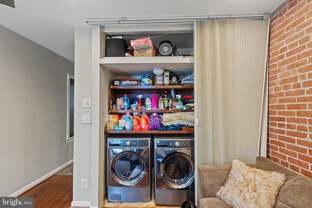 clothes washing area featuring washer and clothes dryer, wood finished floors, and baseboards