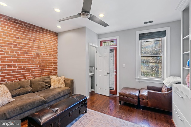 living area featuring brick wall, wood finished floors, a ceiling fan, and recessed lighting