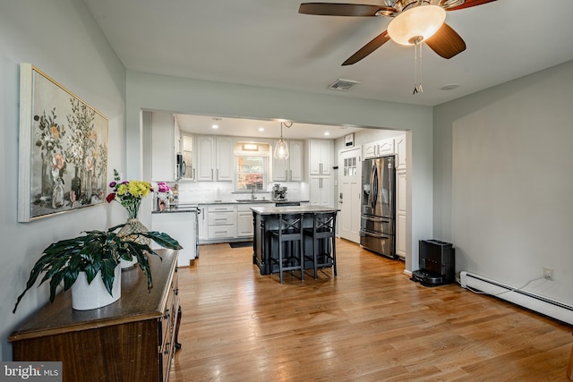40 Hunters Run Rd, Honey Brook, PA 19344 - kitchen featuring appliances with stainless steel finishes, a baseboard radiator, a breakfast bar area, white cabinets, and light wood finished floors