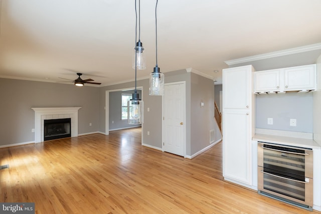 306 Canyon Rd, Winchester, VA 22602 - unfurnished living room with ceiling fan, light wood-style floors, ornamental molding, wine cooler, and a tiled fireplace