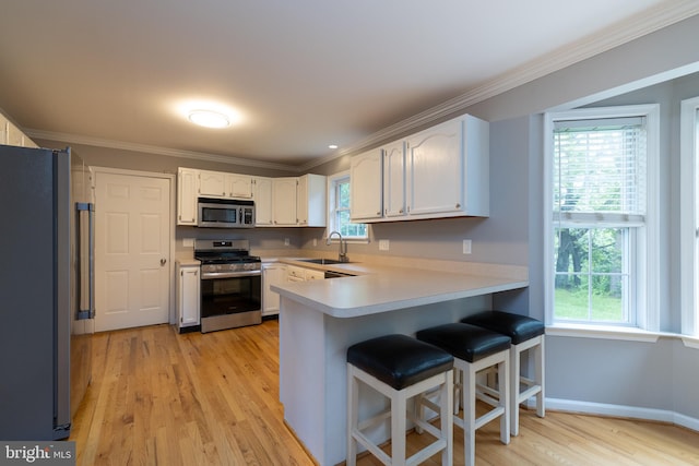 306 Canyon Rd, Winchester, VA 22602 - kitchen featuring appliances with stainless steel finishes, a peninsula, a sink, ornamental molding, and light wood-type flooring