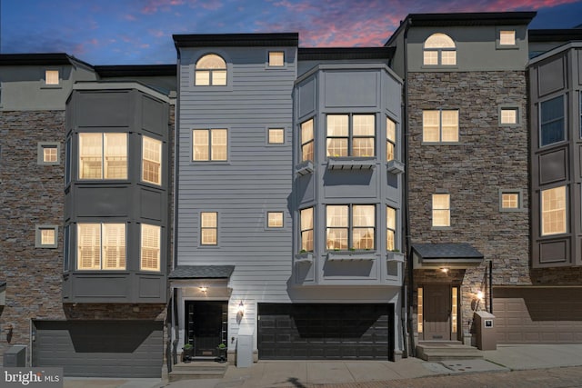304 Dupont St, Philadelphia, PA 19128 - back of property at dusk featuring stone siding, a garage, and entry steps