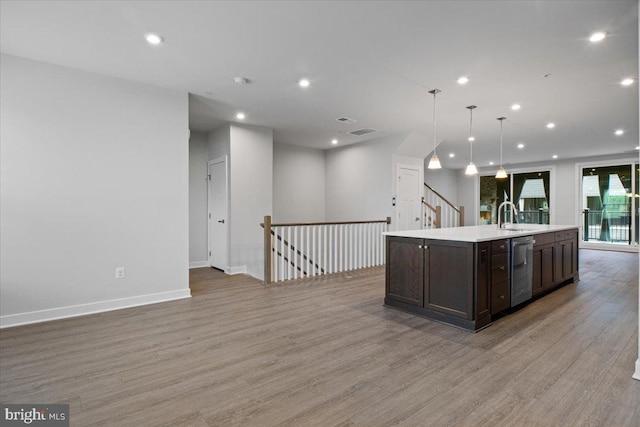 kitchen featuring light wood-style floors, dark brown cabinetry, light countertops, a sink, and dishwasher