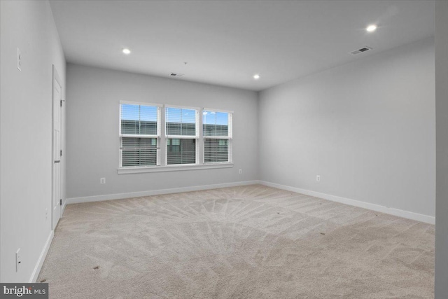 spare room featuring light colored carpet, recessed lighting, and baseboards