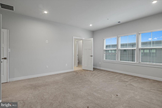 spare room featuring light carpet, baseboards, and recessed lighting