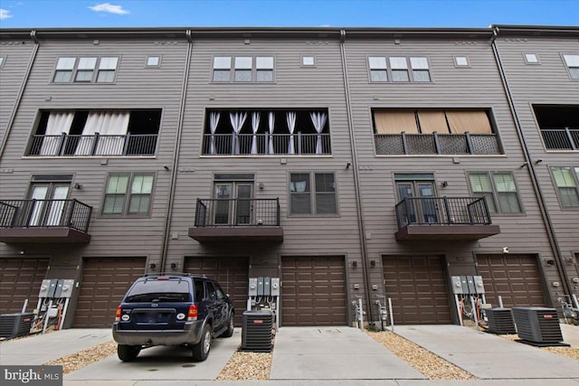 view of building exterior featuring a garage, central air condition unit, and driveway