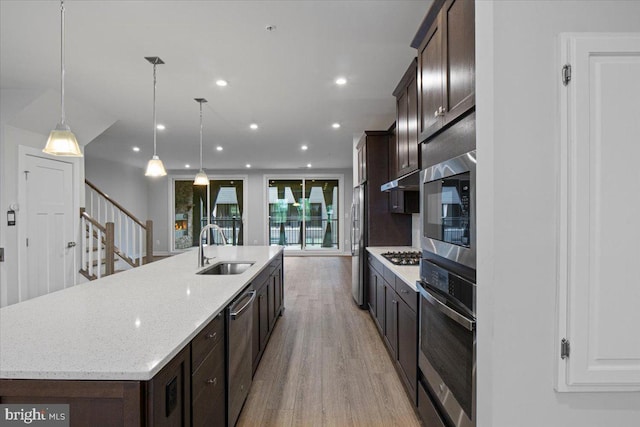 kitchen featuring stainless steel appliances, a sink, dark brown cabinetry, light wood-type flooring, and recessed lighting