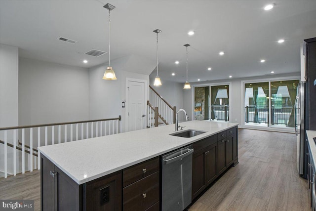 kitchen featuring a sink, dishwasher, light wood finished floors, a large island with sink, and dark brown cabinets