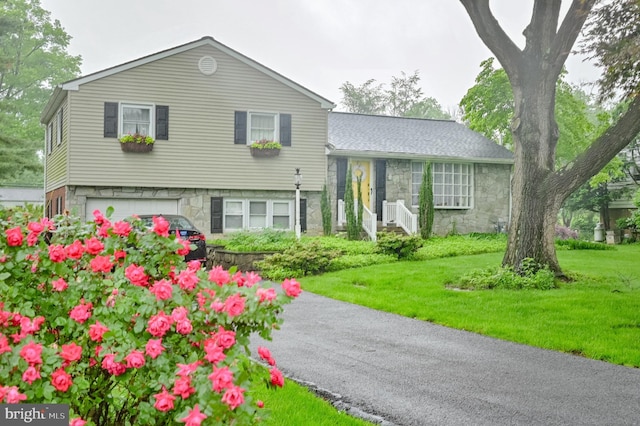 1909 Bloomingdale Ave, Lancaster, PA 17601 - tri-level home with a front yard, an attached garage, and stone siding