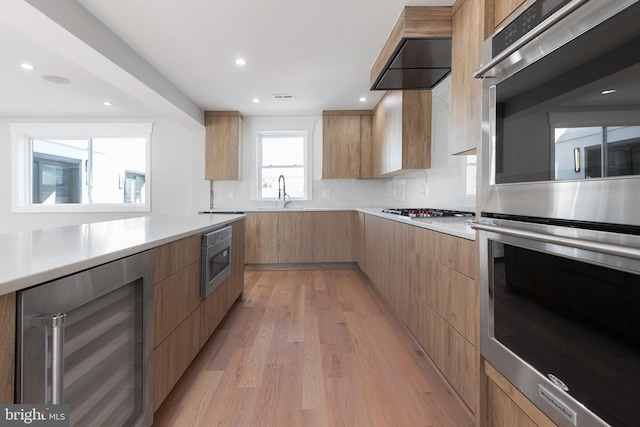 2100 S Pierce St, Arlington, VA 22202 - kitchen featuring modern cabinets, beverage cooler, stainless steel appliances, light countertops, and light wood finished floors
