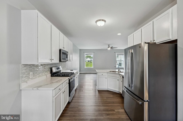 kitchen with stainless steel appliances, a peninsula, a ceiling fan, white cabinets, and dark wood-style floors