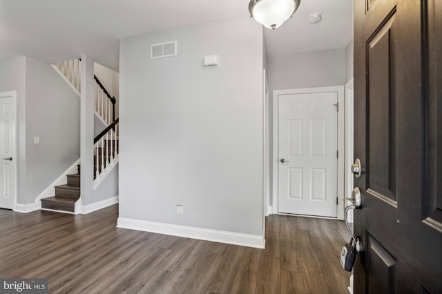 foyer entrance with dark wood-style flooring, stairway, and baseboards