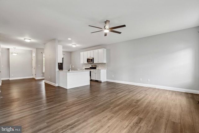 unfurnished living room with a ceiling fan, a sink, baseboards, and dark wood-type flooring
