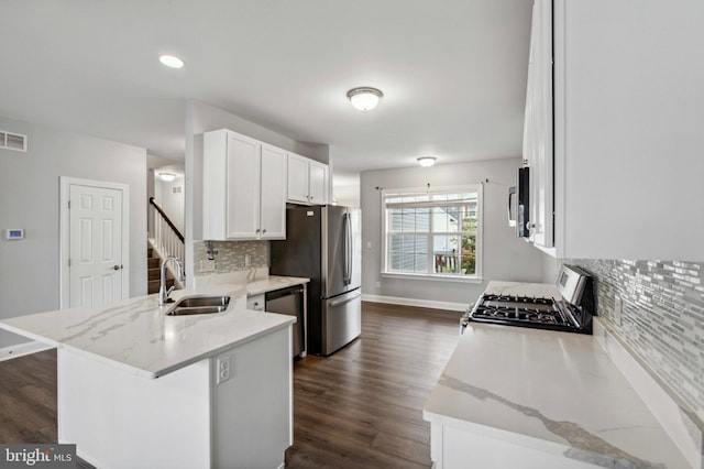kitchen with a sink, appliances with stainless steel finishes, a peninsula, dark wood finished floors, and recessed lighting