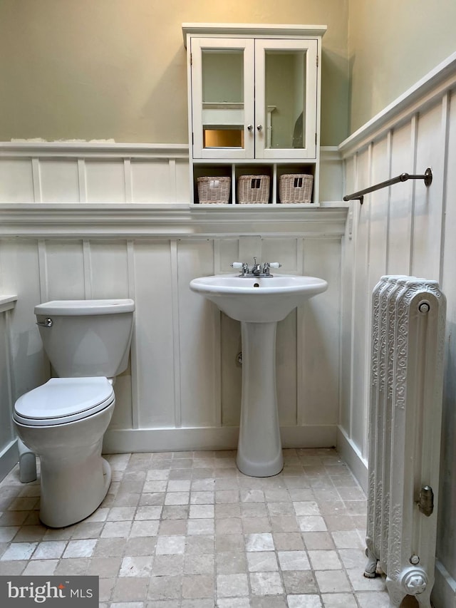 2732 Maryland Ave, Baltimore, MD 21218 - bathroom featuring a decorative wall, radiator heating unit, stone tile floors, toilet, and a wainscoted wall