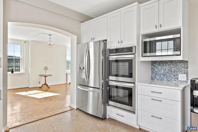 500 Court Sq Unit 503And 504, Charlottesville, VA 22902 - kitchen featuring stainless steel appliances, decorative backsplash, arched walkways, white cabinetry, and baseboards