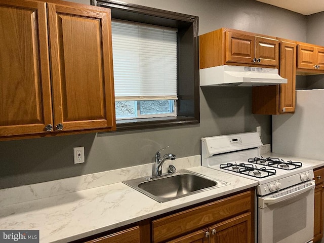 1204 Carl Miller Blvd, Camden, NJ 08104 - kitchen with white range with gas cooktop, under cabinet range hood, a sink, and brown cabinetry