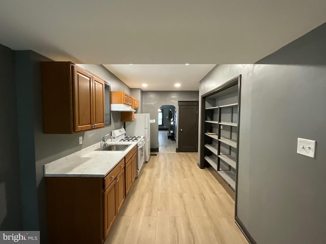1204 Carl Miller Blvd, Camden, NJ 08104 - kitchen with under cabinet range hood, light wood-type flooring, light countertops, white range with gas stovetop, and arched walkways