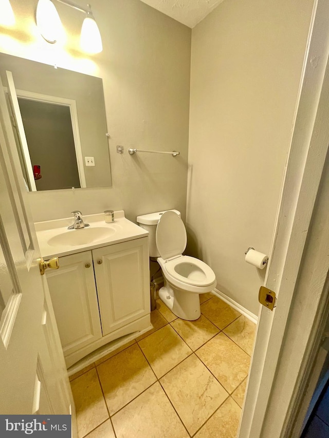 half bath with tile patterned flooring, toilet, and vanity