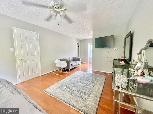 sitting room featuring ceiling fan, a textured ceiling, and wood finished floors