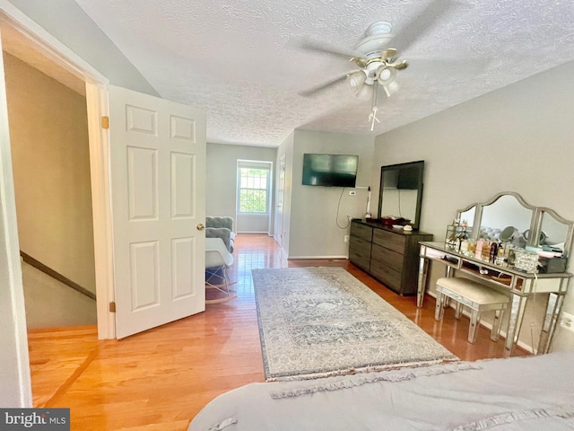 bedroom featuring a textured ceiling, wood finished floors, baseboards, and a ceiling fan
