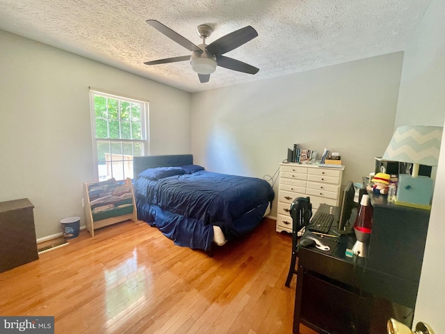 bedroom with hardwood / wood-style flooring, a textured ceiling, and ceiling fan