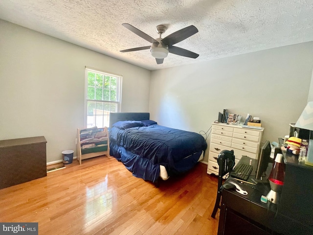 bedroom with wood finished floors, a textured ceiling, and a ceiling fan