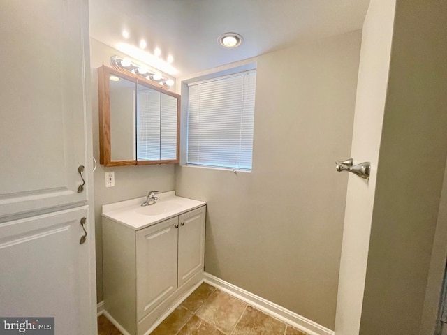 bathroom with baseboards, vanity, and recessed lighting