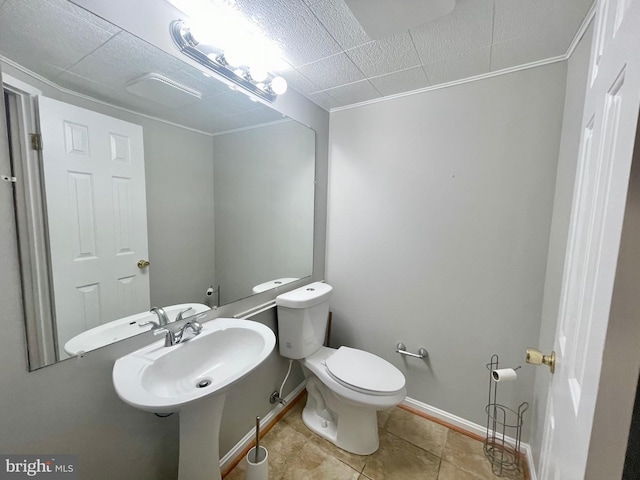 half bathroom with toilet, tile patterned floors, baseboards, and a sink