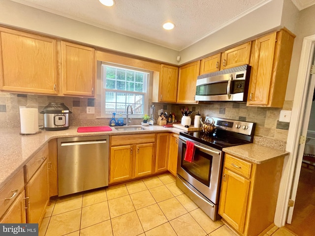 kitchen featuring appliances with stainless steel finishes, a sink, tasteful backsplash, light tile patterned flooring, and a textured ceiling