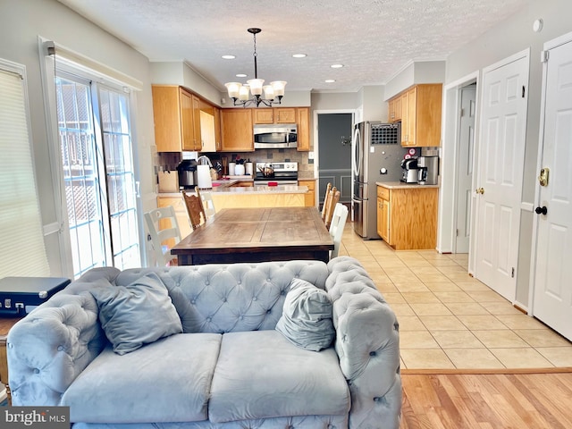 kitchen featuring stainless steel appliances, open floor plan, a chandelier, backsplash, and light countertops