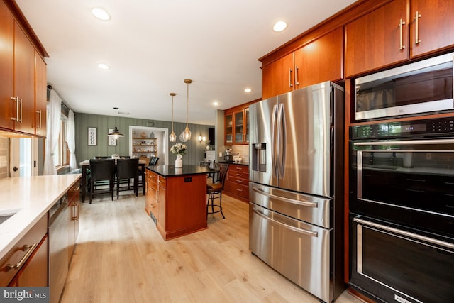 kitchen featuring appliances with stainless steel finishes, light wood-style floors, a kitchen bar, recessed lighting, and hanging light fixtures