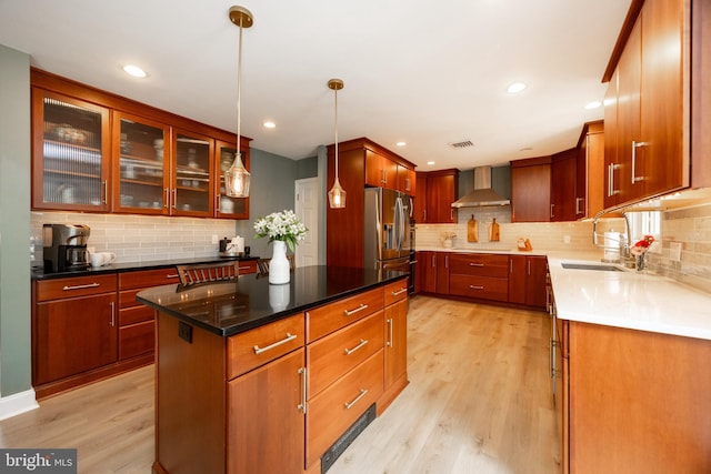 kitchen with stainless steel refrigerator with ice dispenser, wall chimney exhaust hood, a sink, decorative backsplash, and recessed lighting