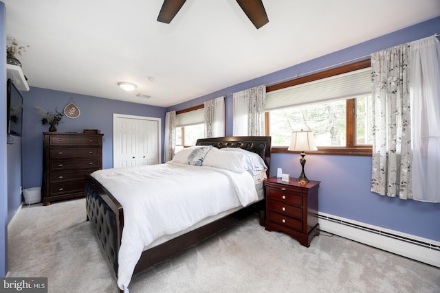 bedroom with a baseboard radiator, carpet flooring, a closet, a ceiling fan, and baseboards