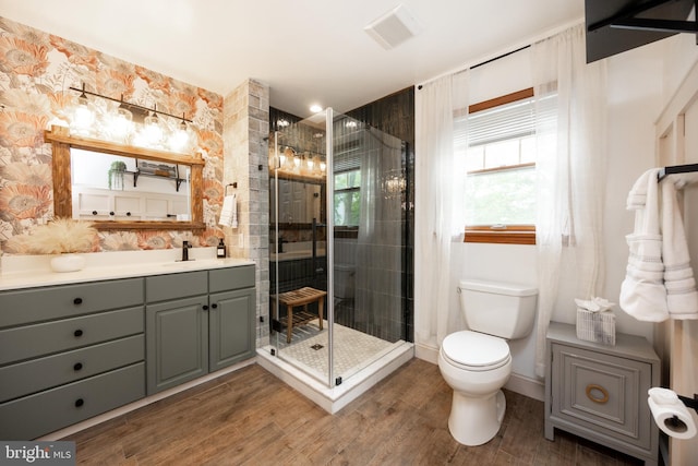 bathroom featuring wood finished floors, toilet, a shower stall, and vanity