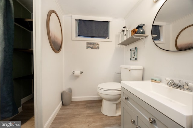 bathroom with wood finished floors, toilet, baseboards, vanity, and crown molding